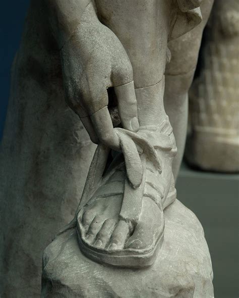 hermes leaning forward to tie his sandal coin|Hermes wearing sandals.